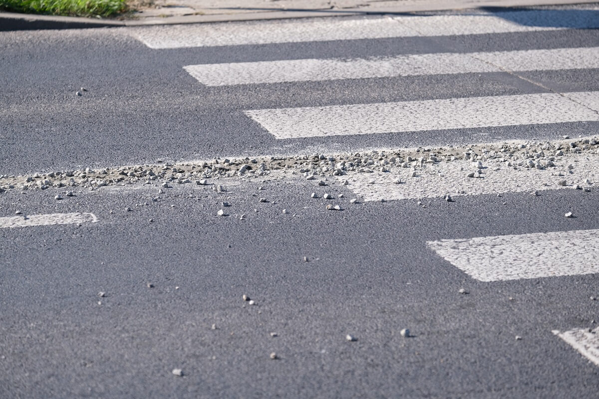 Rozlany beton z kamieniami na jezdni na ul. Podzamcze