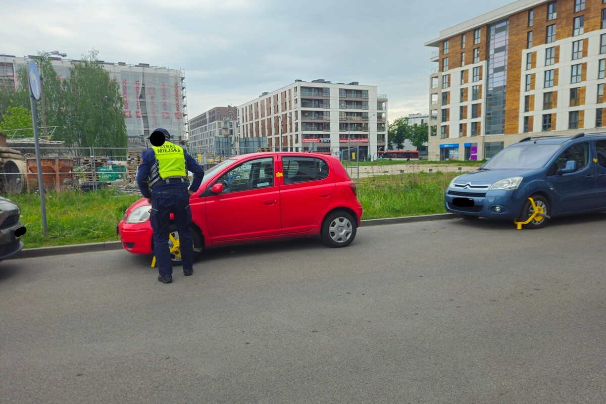 Strażnik miejski zakładający blokady na samochody na ul. Wojciechowskiej
